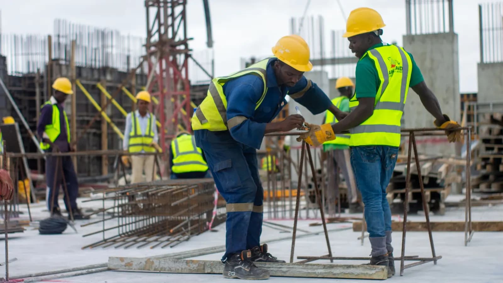 Construction crew in hard hats and high-visibility vests working on rebar at a building site