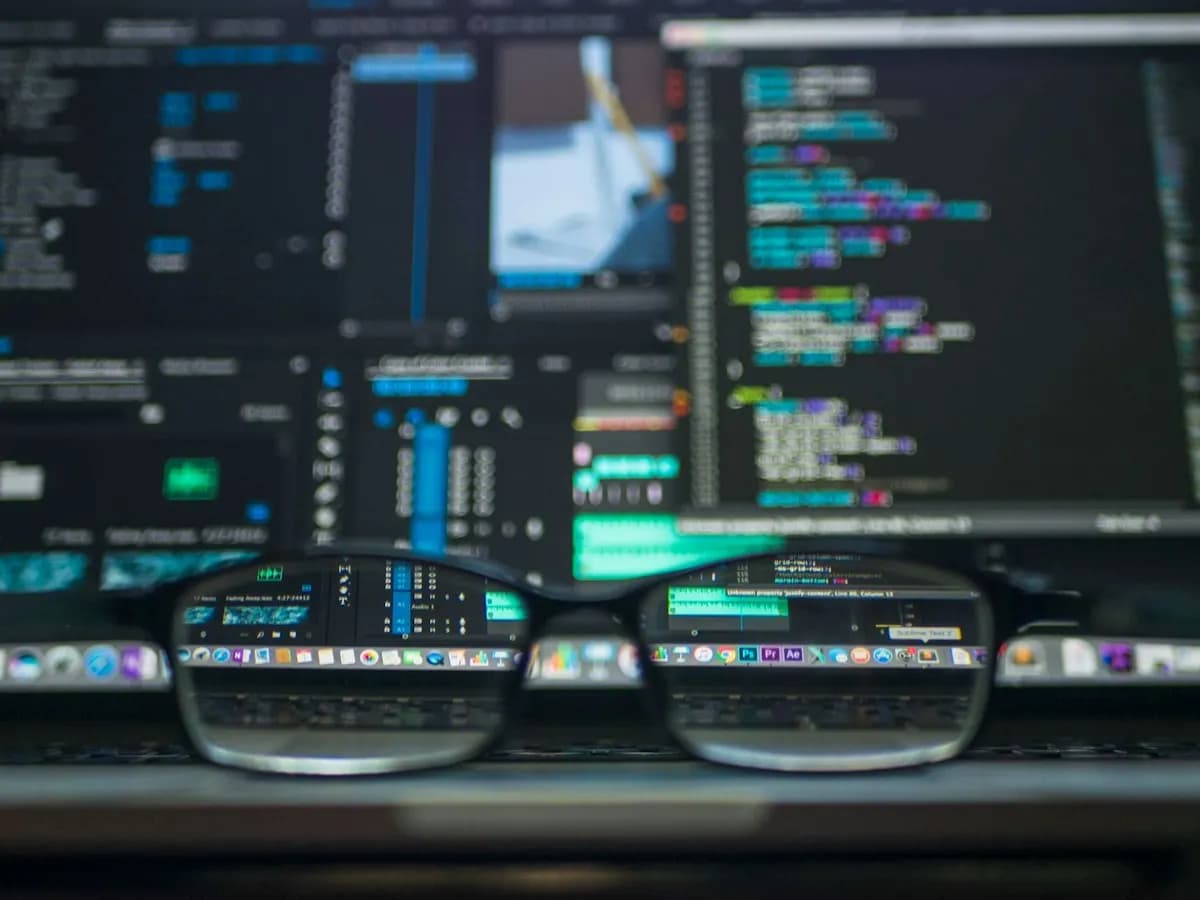 Eyeglasses in front of a blurred screen of code, with the lenses bringing it into focus