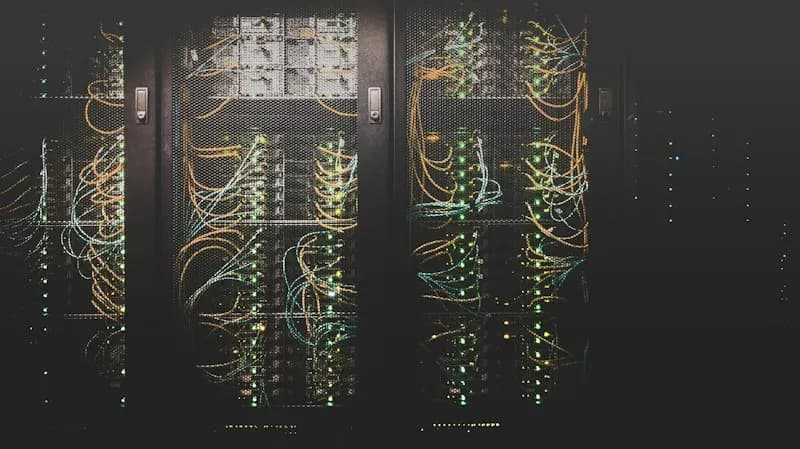 Dark server racks packed with orange and blue network cables and green status lights