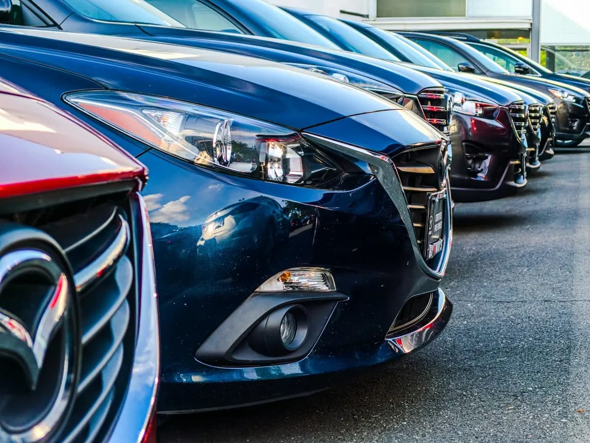Close-up of new cars parked in a tight row, showing headlights and chrome grilles
